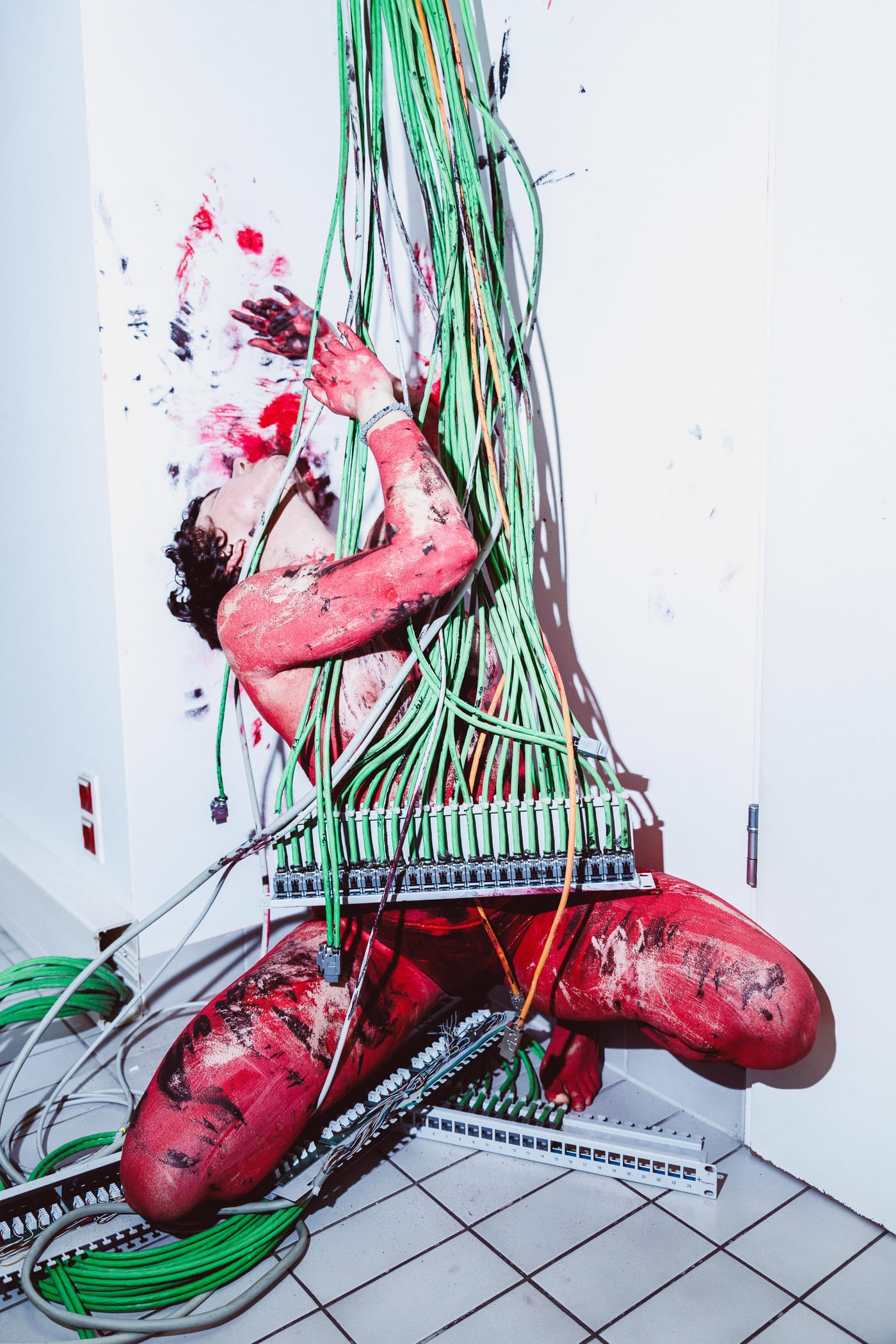 Figure in red paint tangled in green cord